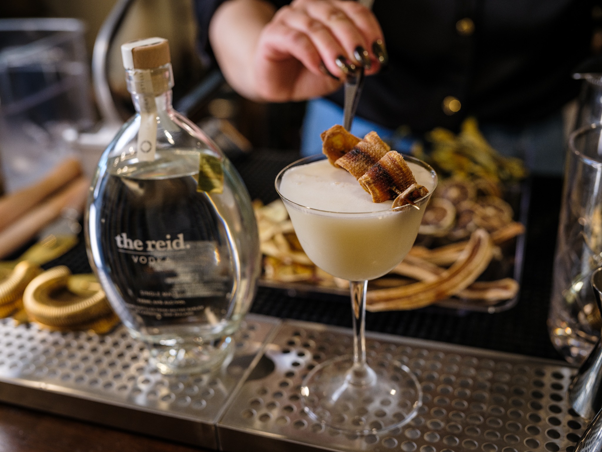 Bartender finishing a cocktail beside a spirits bottle