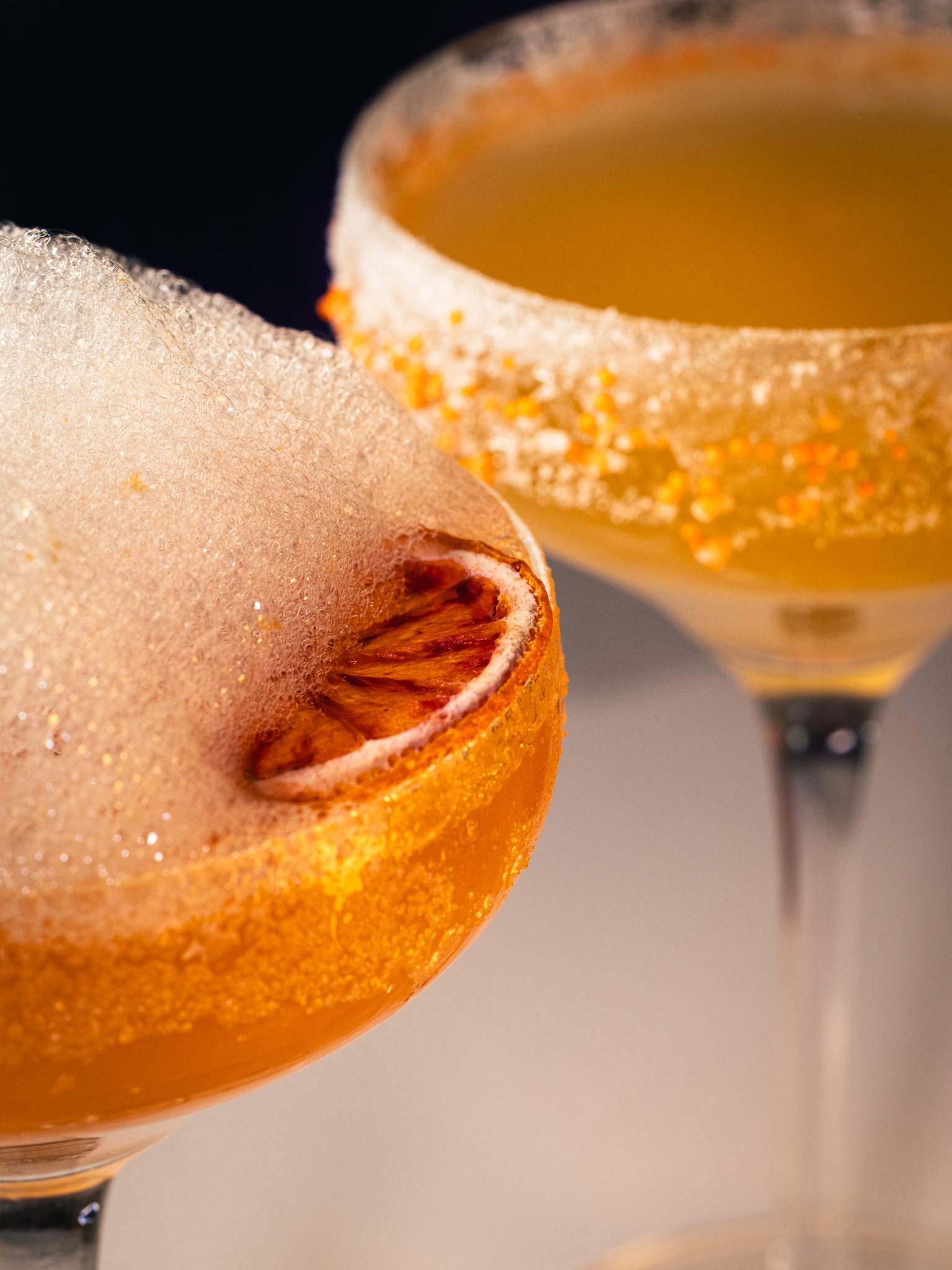 Close-up of golden cocktails with sugared rims and citrus