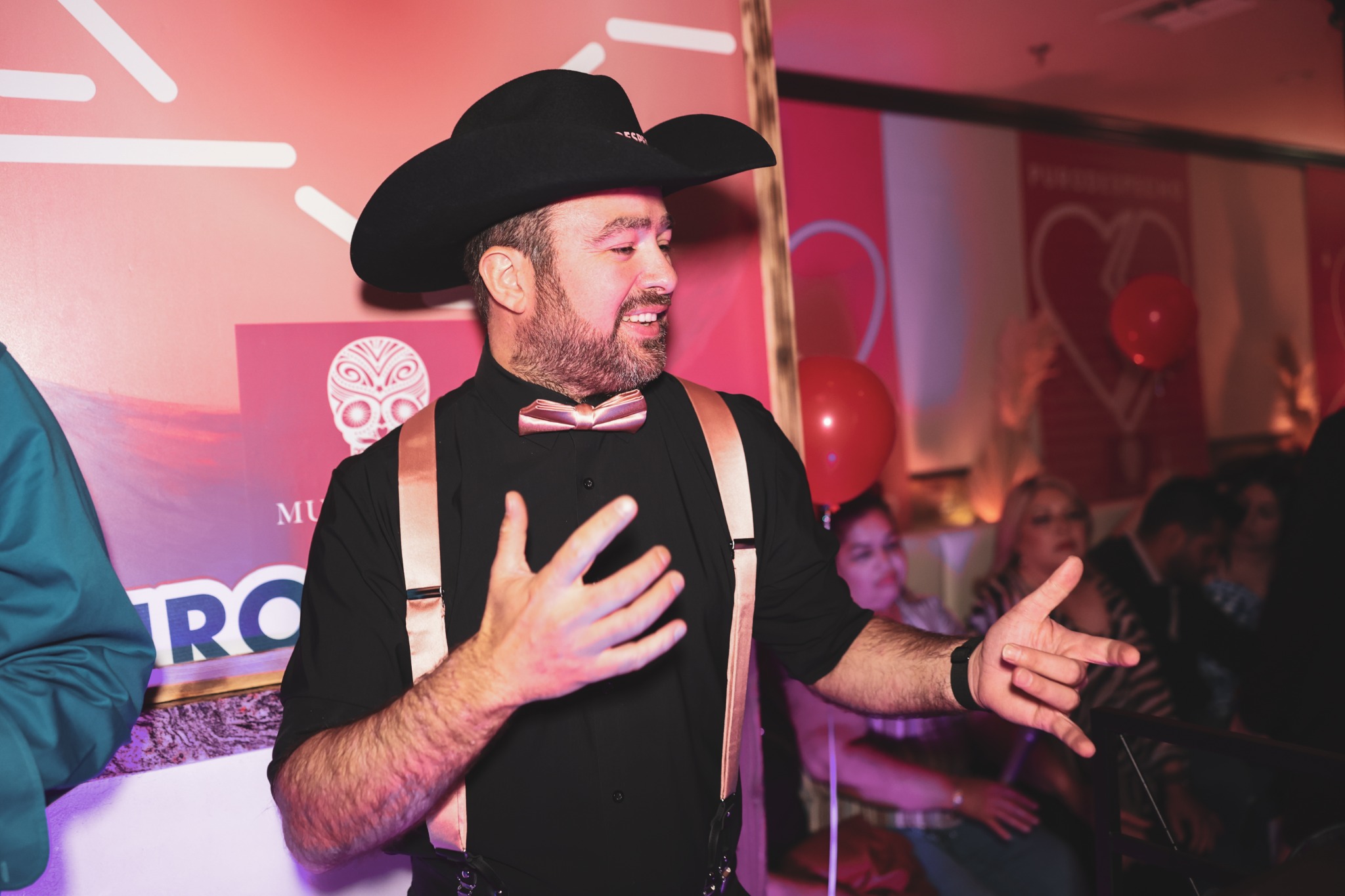 Guest in a black cowboy hat gesturing during a celebration