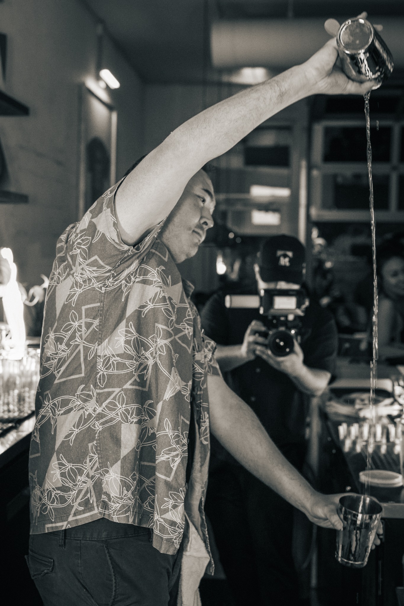 Black-and-white photograph of a bartender making a long pour