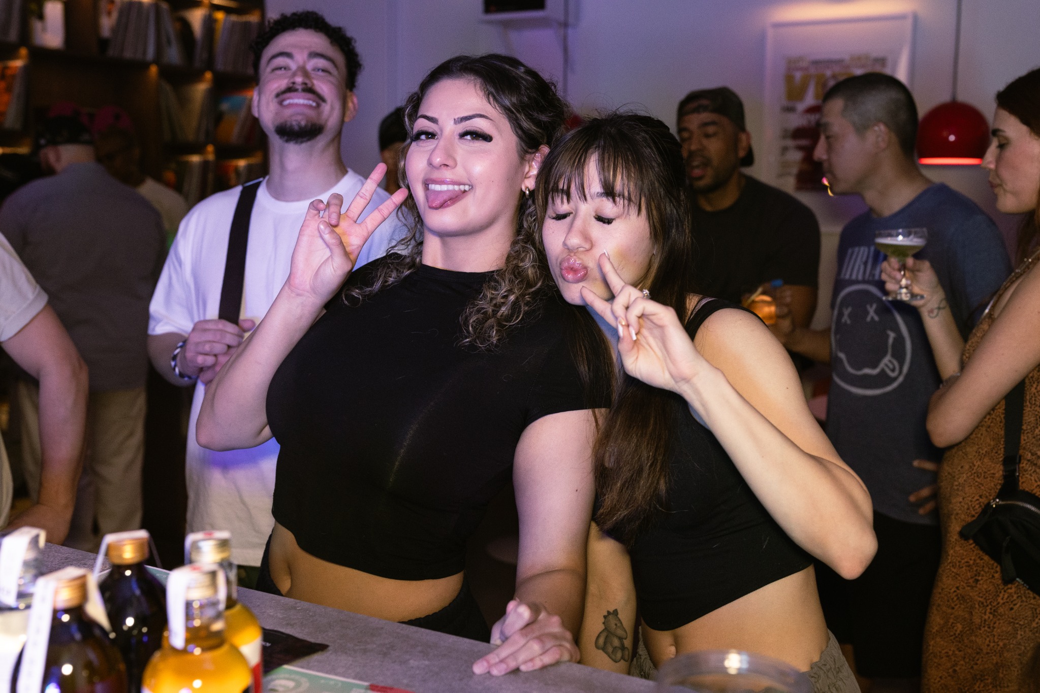 Two guests posing playfully at the bar with friends behind them