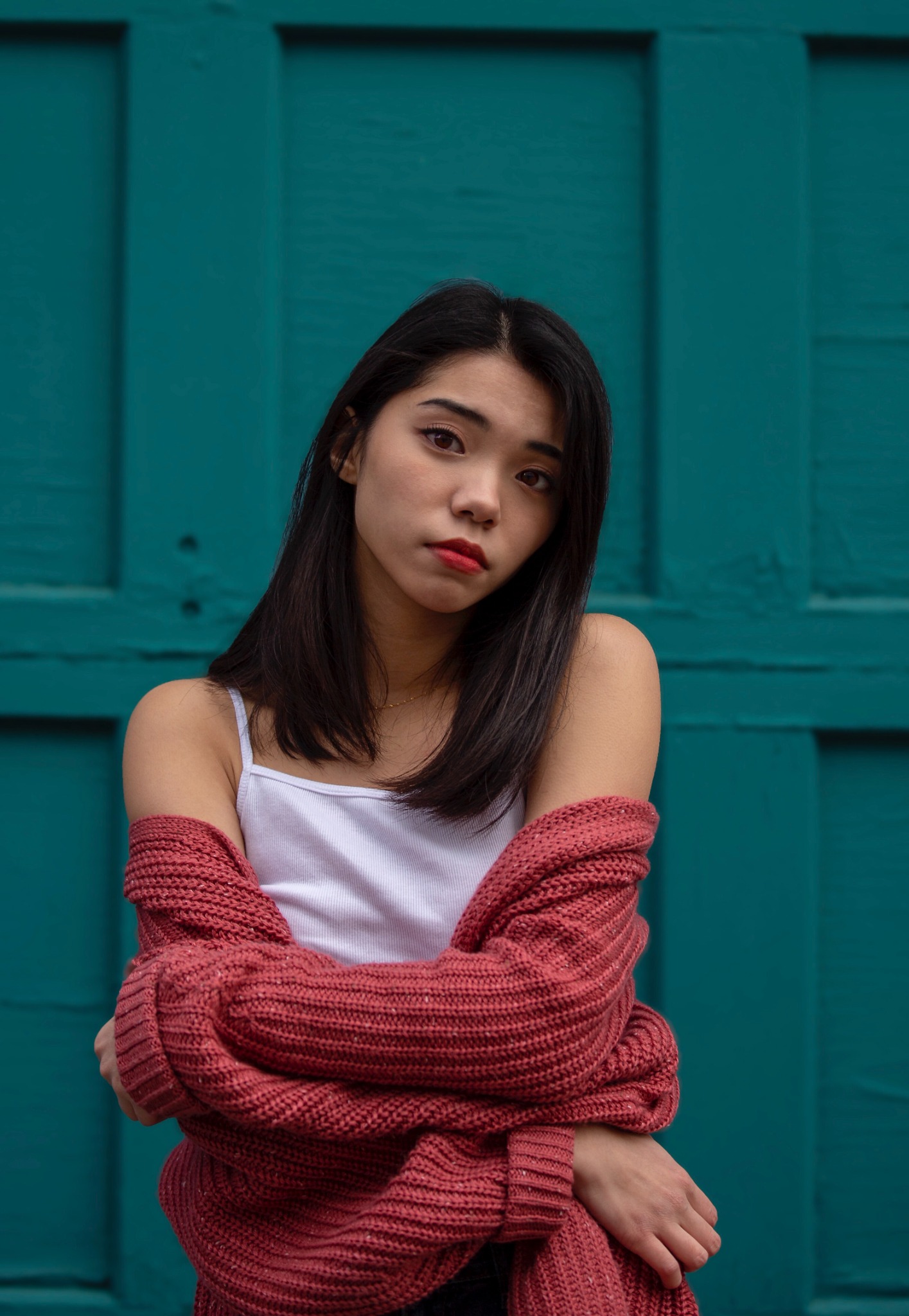 Portrait in a red cardigan against a teal door