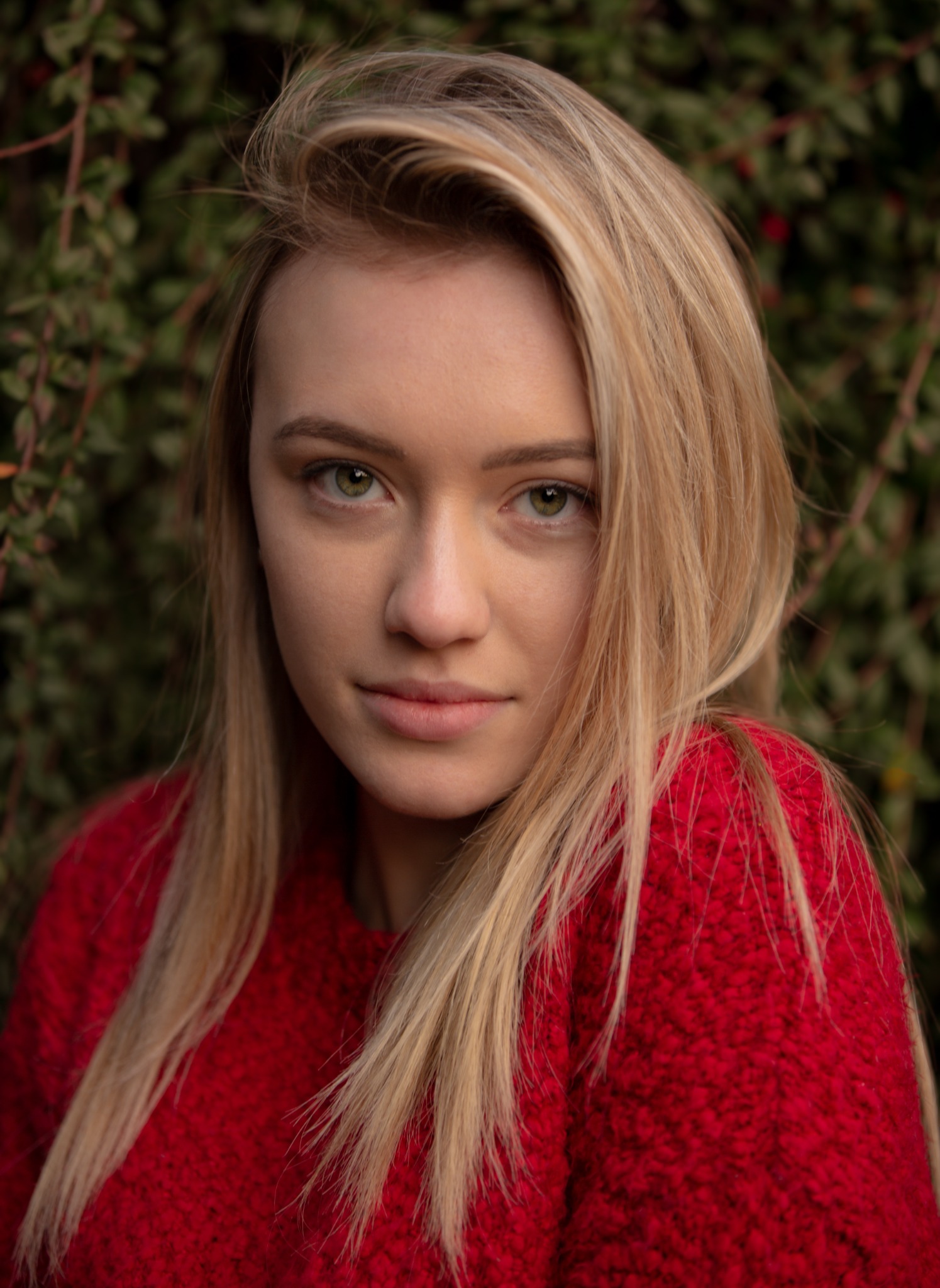 Close-up portrait in a red sweater against foliage
