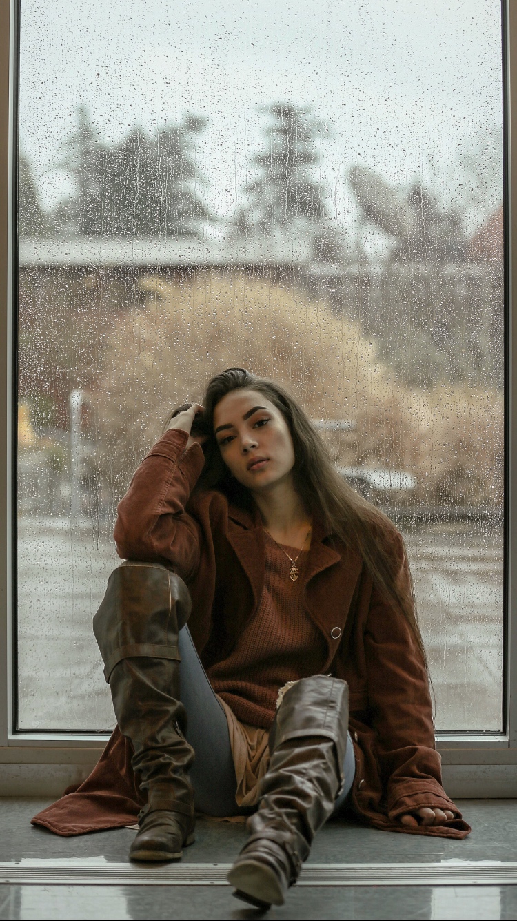 Environmental portrait seated beside a rain-speckled window