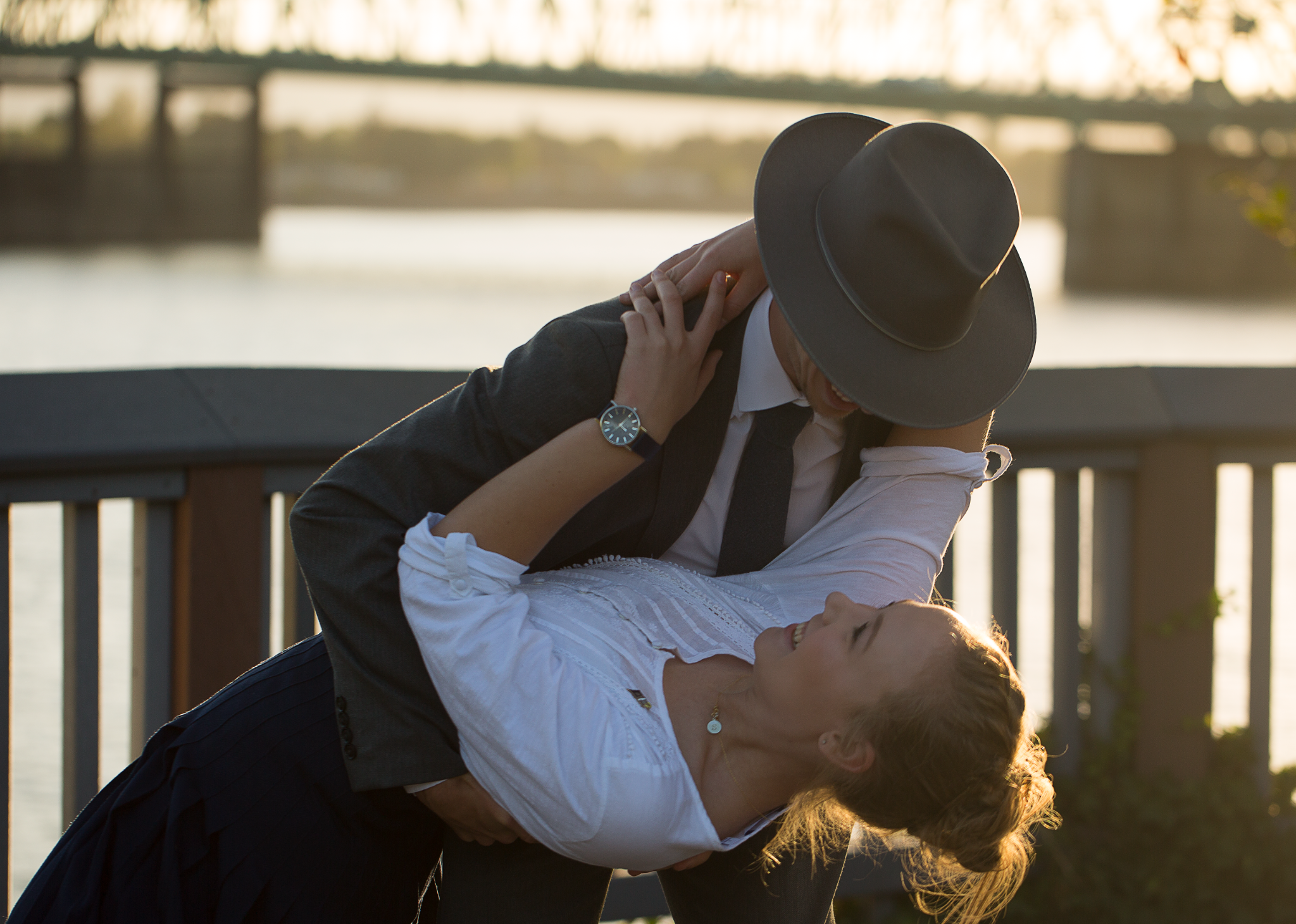 A couple sharing a playful dip beside the river at sunset