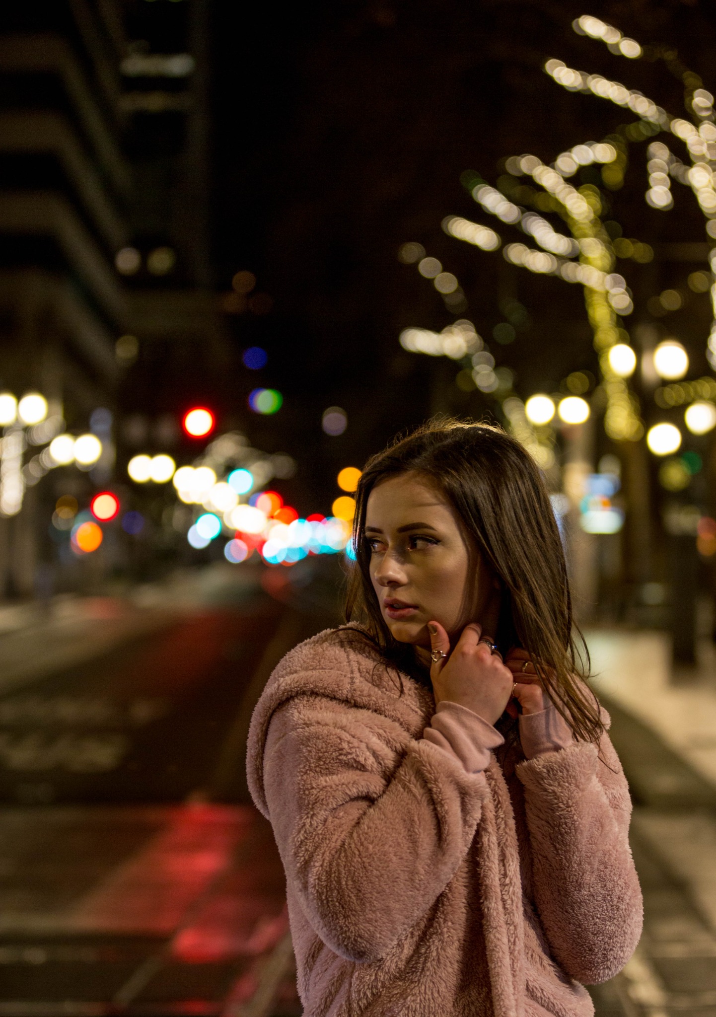 Nighttime portrait with city lights and a pink coat